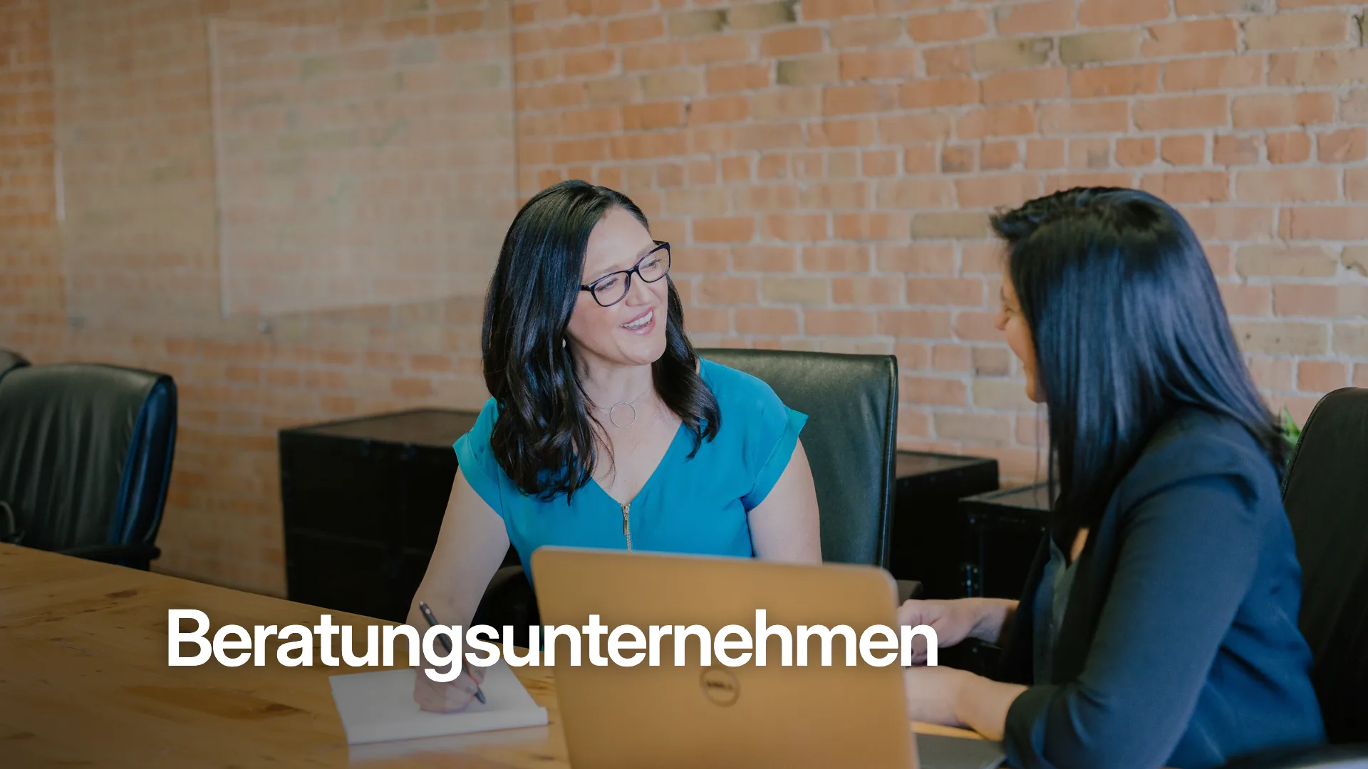 Zwei Frauen im Gespräch an einem Besprechungstisch mit Laptop, unten links das Wort Beratungsunternehmen