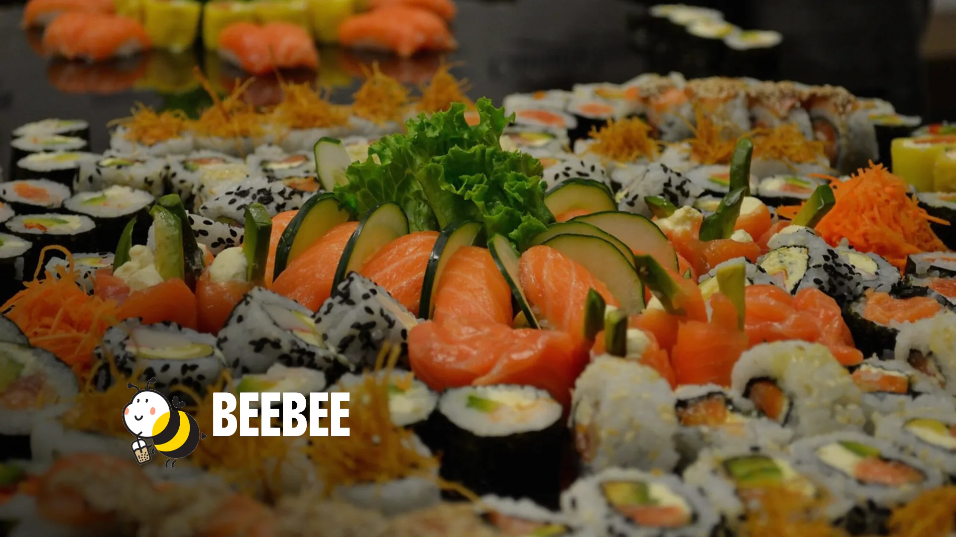 Sushi-Platte mit Lachs, Maki und Gurke, unten links das Logo von BeeBee