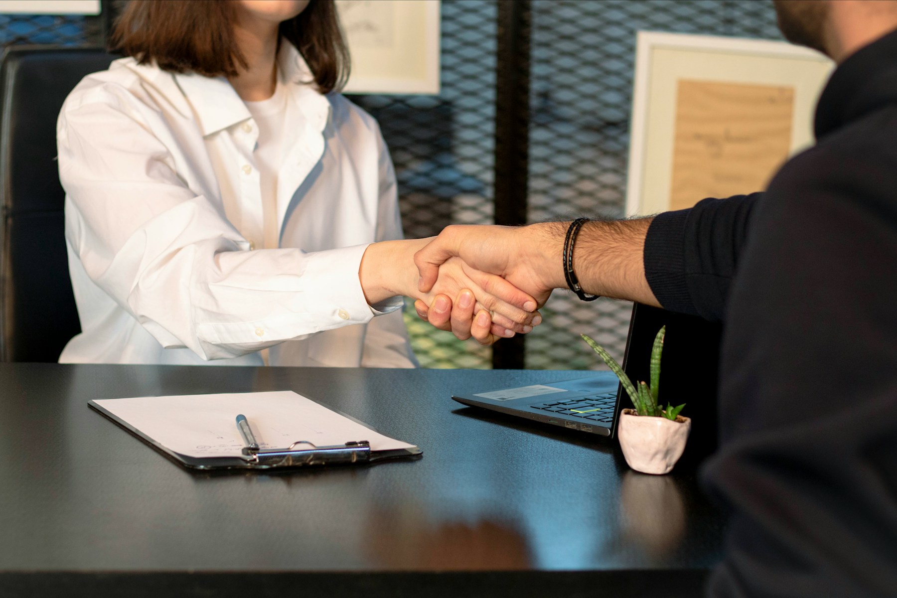 Begrüßung einer neuen Mitarbeiterin mit Handschlag am Arbeitsplatz