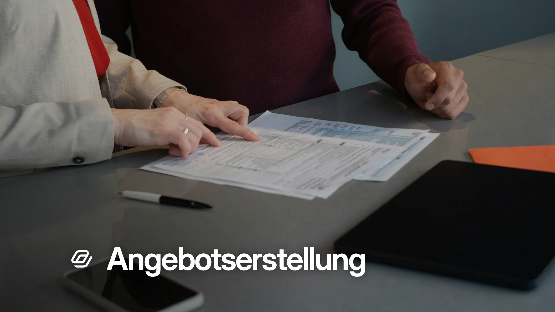 Zwei Personen gehen ausgedruckte Unterlagen am Tisch durch